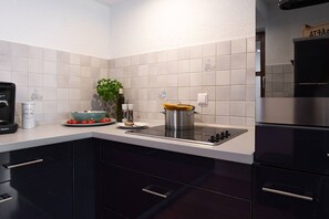 A modern kitchen with a built-in stove, dark cabinets, and white tiled backsplash.