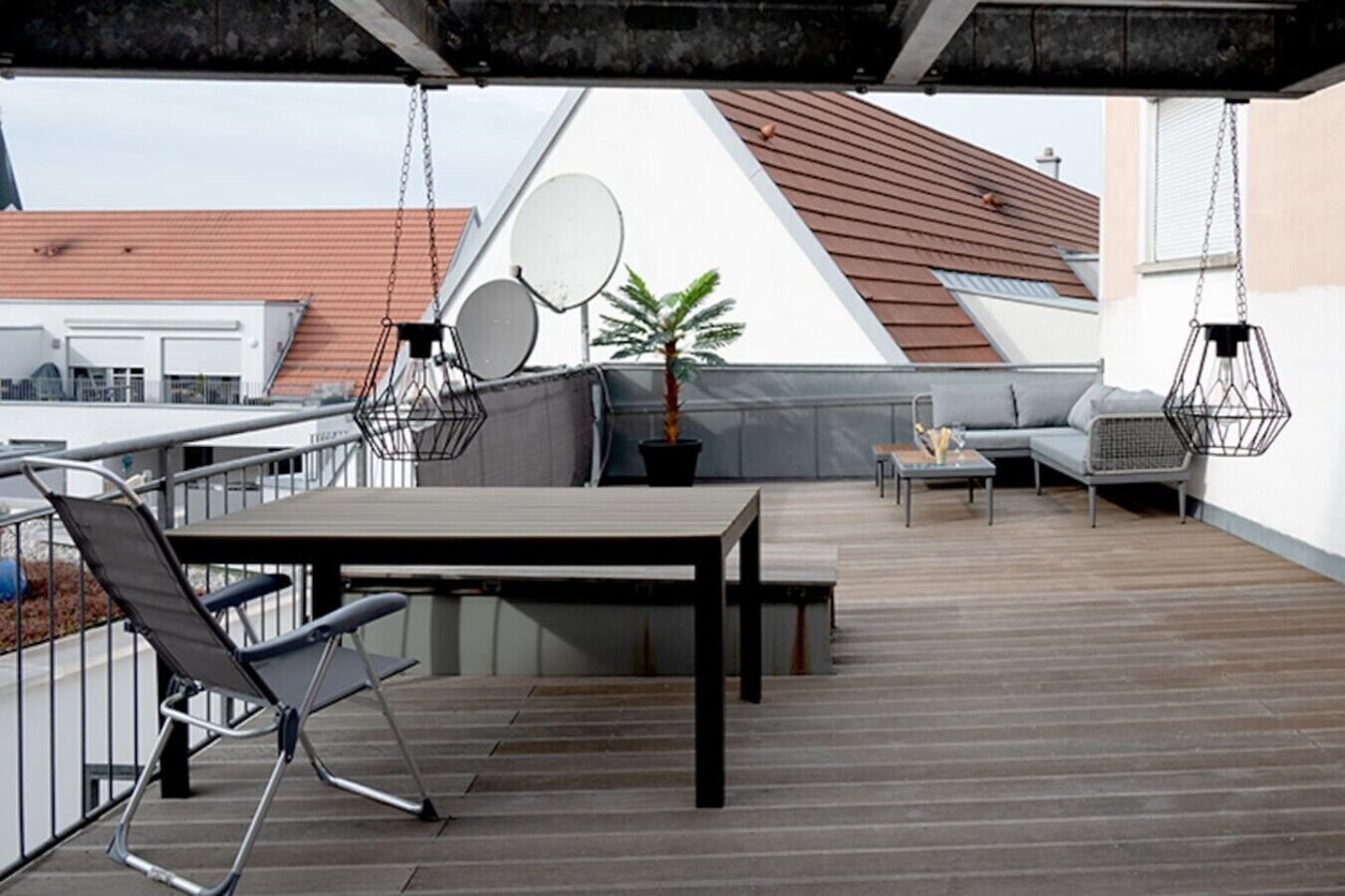 Eine Dachterrasse mit Tisch, Stühlen, einer Sitzecke und einem Blumentopf.