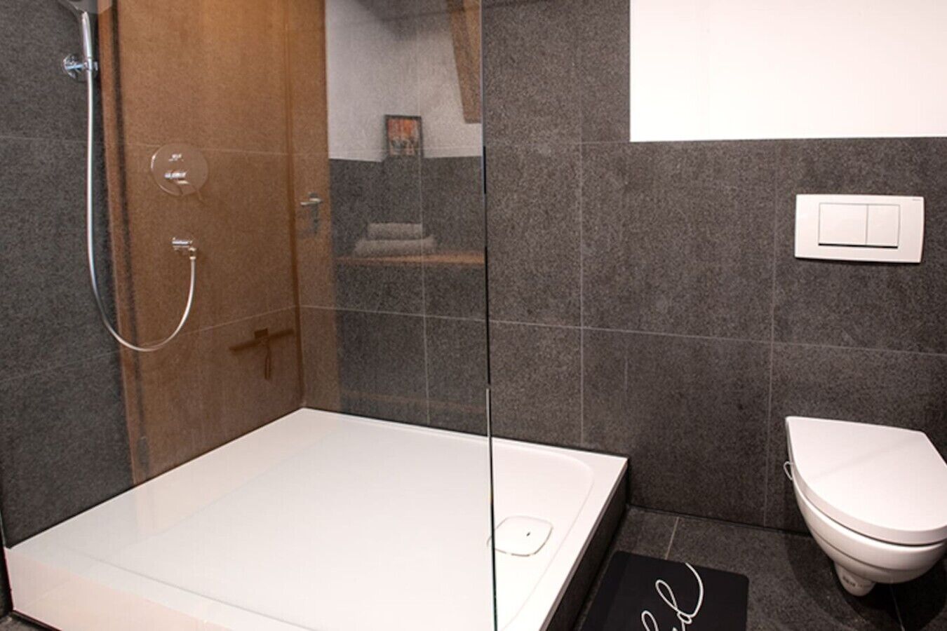 Une salle de bain moderne avec une douche à parois de verre, une baignoire blanche et des toilettes.