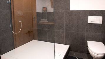 Une salle de bain moderne avec une douche à parois de verre, une baignoire blanche et des toilettes.