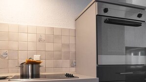 A modern kitchen with a built-in oven, a stove, and dark cabinetry.