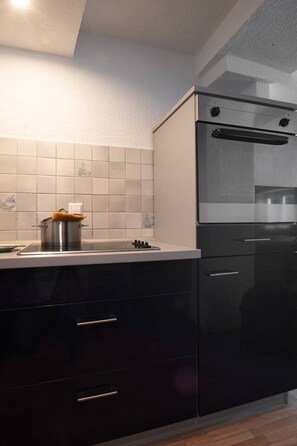 A modern kitchen with a built-in oven, a stove, and dark cabinetry.