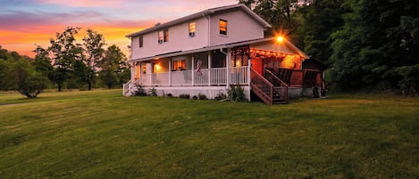 A two-story house with a porch and a staircase leading to a deck.