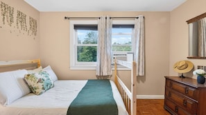 A bedroom with a bed, a dresser, a window with curtains, and a view of trees outside. - Ohana Nature Escape by Avantstay Creekside + Firepit + Grill Waterfall + Beaver Pond Walks (Catskill)