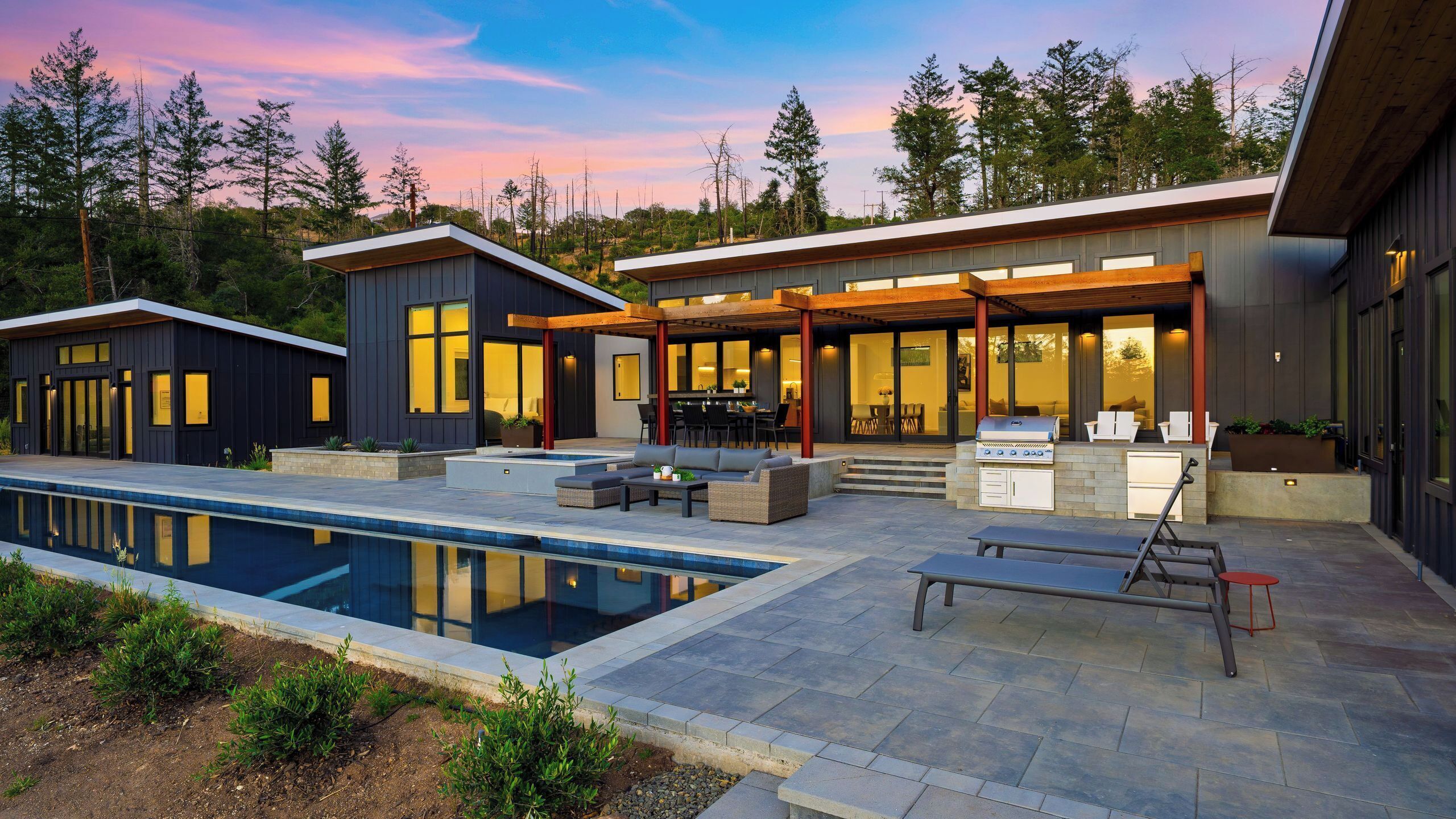 A modern two-story house with a swimming pool, outdoor seating, and a barbecue area.