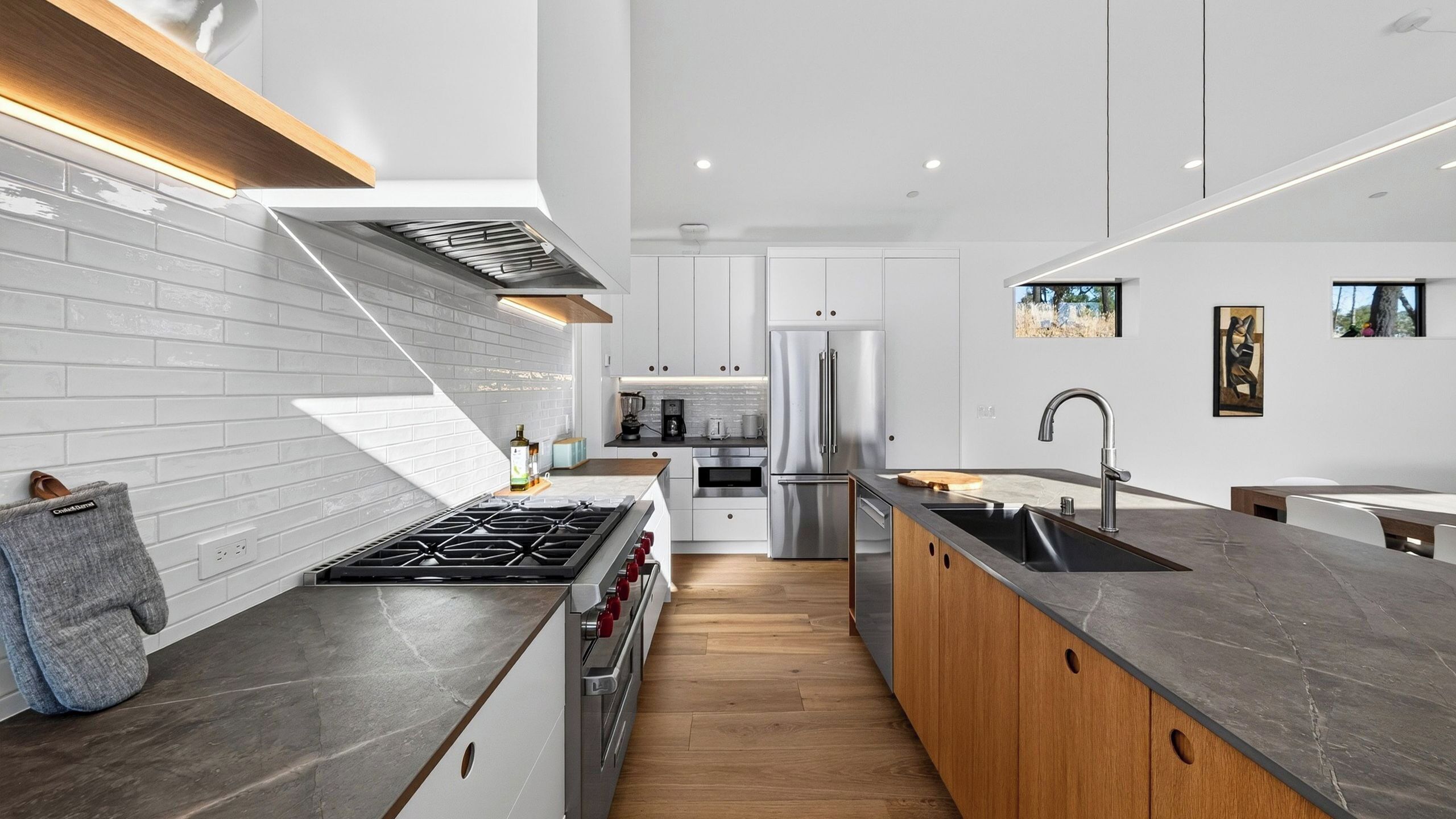 A modern kitchen with a central island, stainless steel appliances, and a wooden countertop.