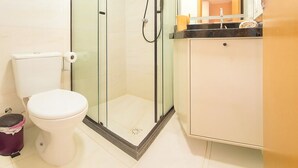 Un baño con ducha de mampara de vidrio, inodoro y lavabo con espejo.