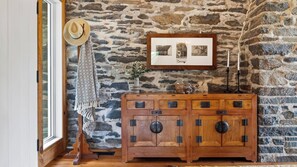 A rustic interior with a stone wall, a wooden cabinet with multiple drawers, a hat on a hook, and a framed photograph above the cabinet. - Ashokan Acres by Avantstay Private 125-acre Retreat Pond + Hot Tub + Sauna + Trails (Kingston)