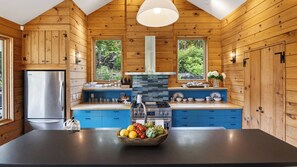 A modern kitchen with wooden walls, a central island, and a stainless steel refrigerator. - Ashokan Acres by Avantstay Private 125-acre Retreat Pond + Hot Tub + Sauna + Trails (Kingston)