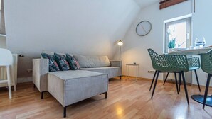Un espace de vie moderne comprenant un canapé, une table à manger avec des chaises, une lampe et une horloge murale.