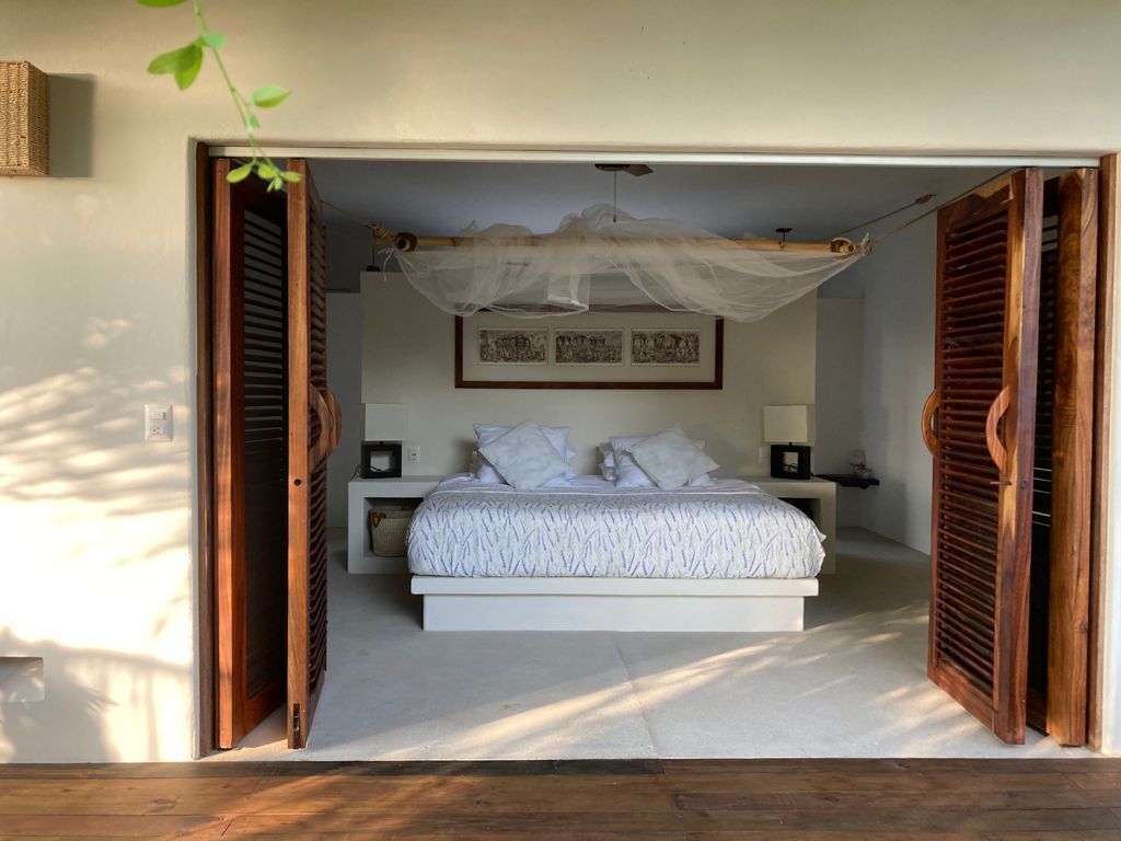 Un dormitorio con cama, mesitas de noche, dosel y un cuadro enmarcado en la pared.
