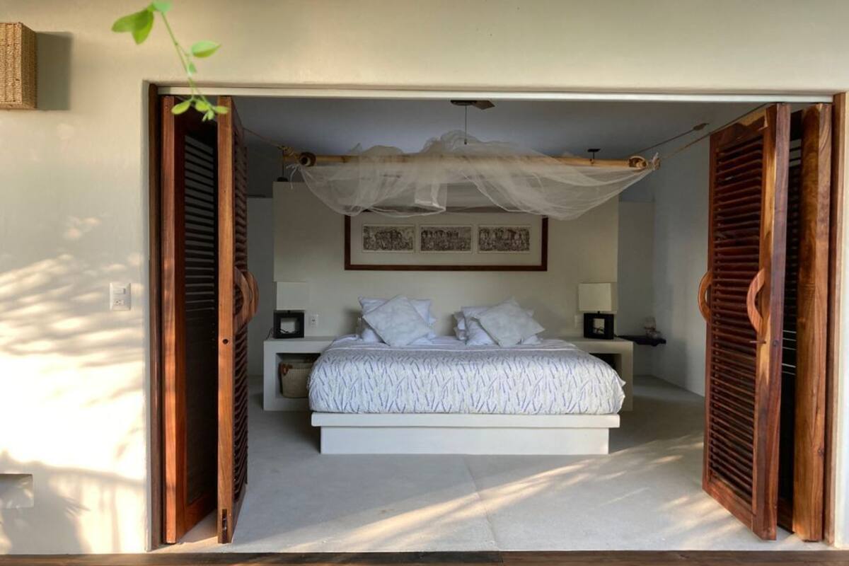 A bedroom with a bed, bedside tables, a canopy, and a framed picture on the wall.