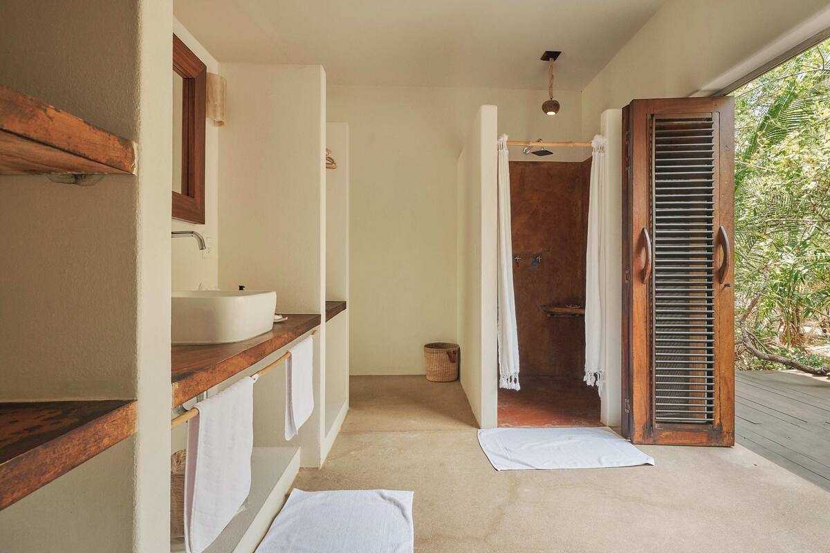 A bathroom with a wooden vanity, a sink, and a shower with a wooden door.