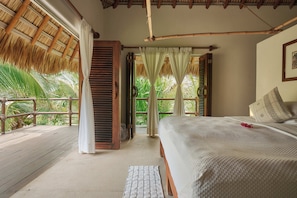 Una habitación con cama, ventana con cortinas, techo de madera y vistas a la vegetación.