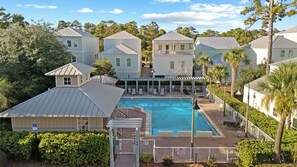 A residential area with a swimming pool, multiple houses, and a covered patio area. - Serene on 30A by Avantstay Golf Cart + Pool + Game Room Steps to Beach (Santa Rosa Beach)