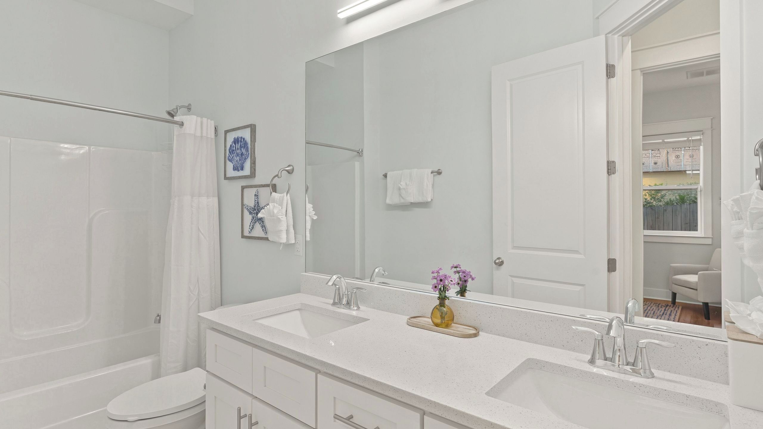 A modern bathroom with a shower, two sinks, a large mirror, and a toilet.