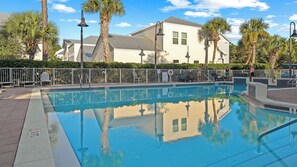 A swimming pool with a white fence, lounge chairs, and palm trees. - Serene on 30A by Avantstay Golf Cart + Pool + Game Room Steps to Beach (Santa Rosa Beach)
