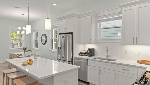 A modern kitchen with white cabinetry, stainless steel appliances, and a central island. - Serene on 30A by Avantstay Golf Cart + Pool + Game Room Steps to Beach (Santa Rosa Beach)