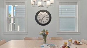 Un coin repas agrémenté d’une horloge murale ronde, d’un vase avec des fleurs et d’une table mise pour le petit-déjeuner.
