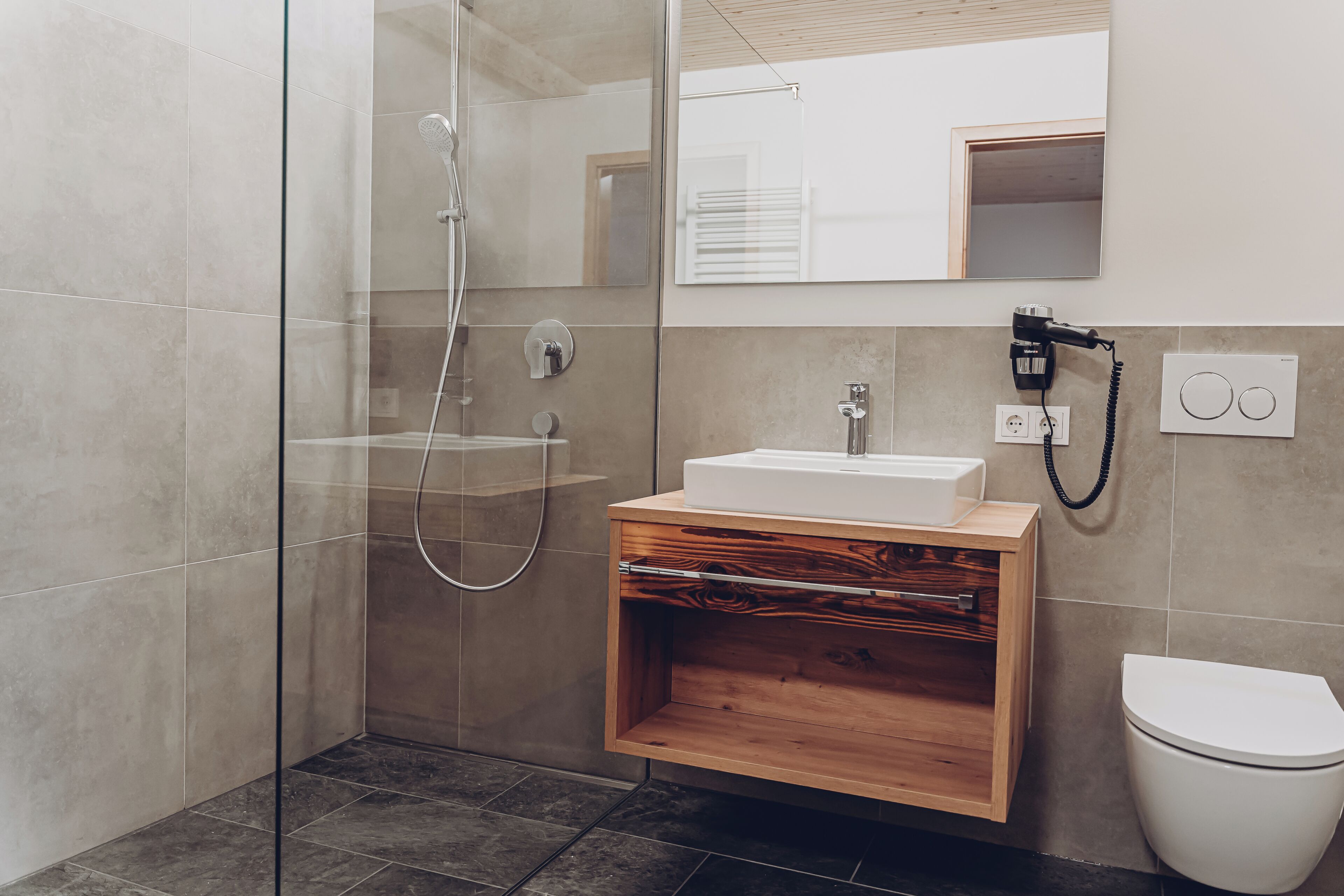 Une salle de bain moderne avec une douche à parois de verre, un meuble-lavabo en bois et des toilettes.