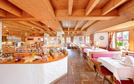 A restaurant with wooden beams, a bar area, and tables set for dining.
