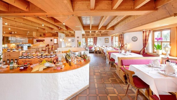 Un restaurant amb bigues de fusta, una zona de bar i taules preparades per dinar.