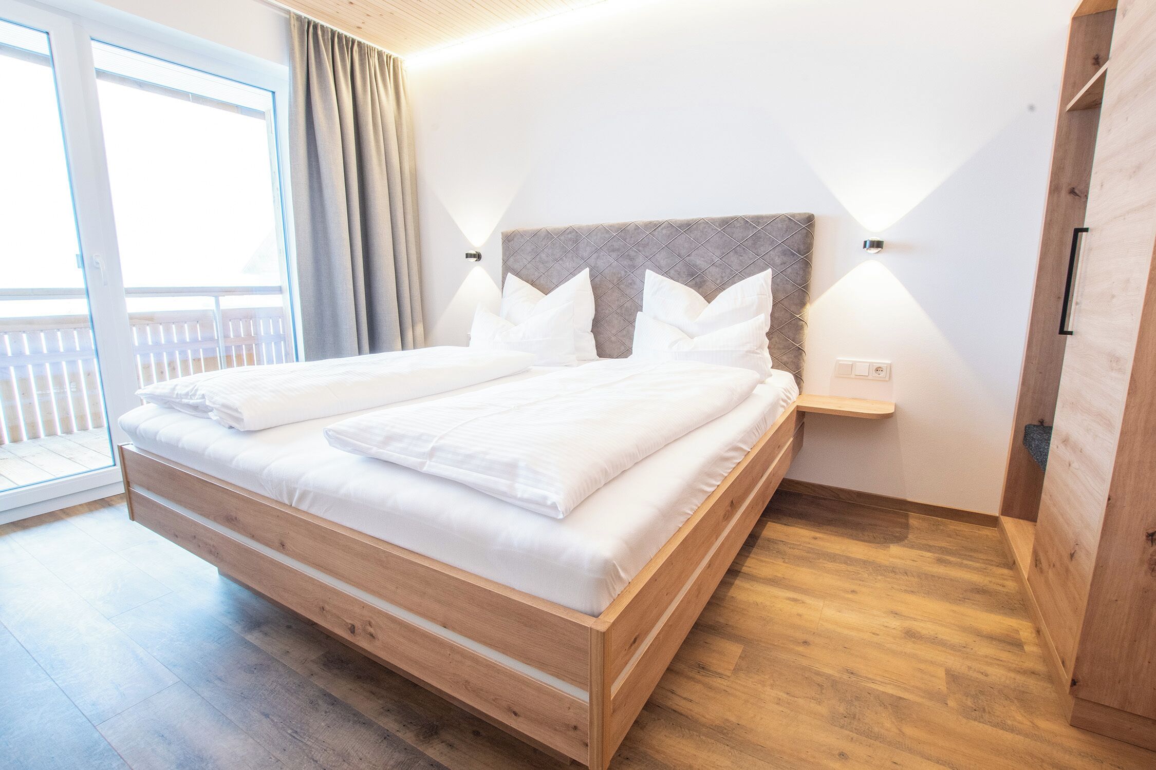 Un dormitorio moderno con estructura de cama de madera, cabecera con diseño de rombos y mesita de noche con lámpara.