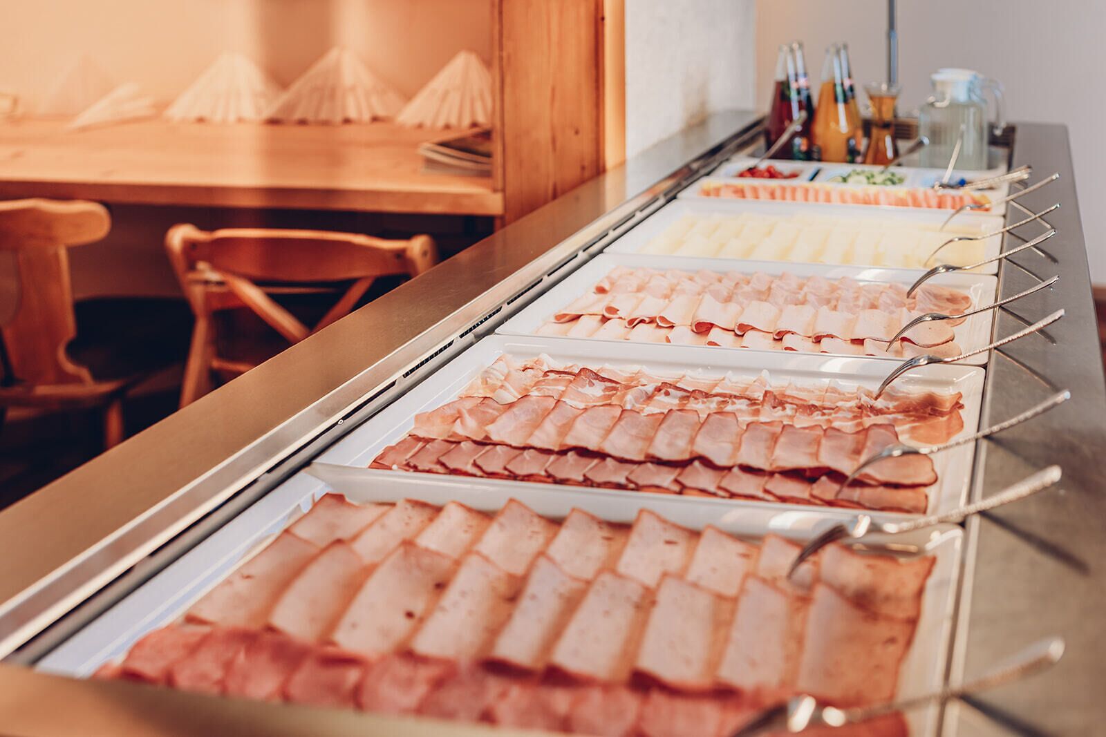 A buffet with various meat options and utensils.