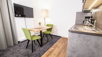 Eine kleine Küche mit Spüle, einer Kaffeemaschine und einem Tisch mit zwei Stühlen.