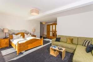 Una habitación con una cama de madera, un sofá verde, una pequeña mesa de madera y una lámpara.