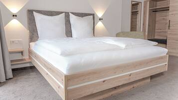 A bedroom with a wooden bed, two wall-mounted lights, a nightstand, and a wardrobe.
