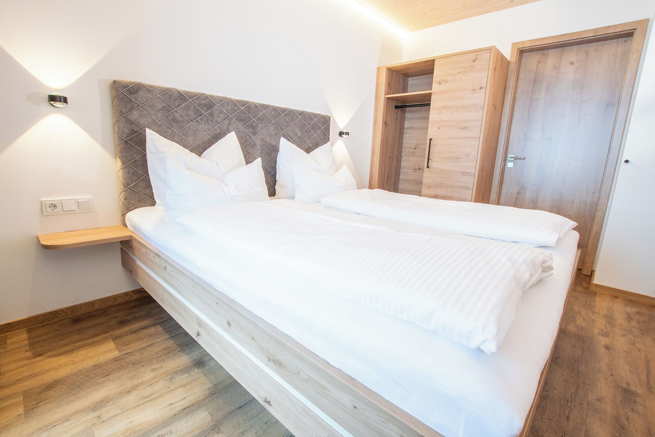 Un dormitorio con una cama, una mesita de noche, un cabecero de madera y un armario.