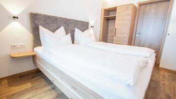 Un dormitorio con una cama, una mesita de noche, un cabecero de madera y un armario.