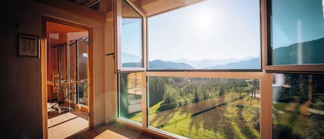 A room with large windows offering a view of a mountainous landscape.