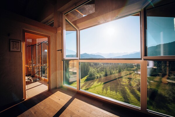 A room with large windows offering a view of a mountainous landscape.