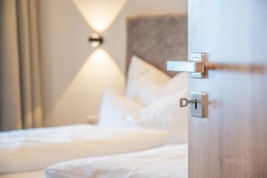 A hotel room with a bed, a nightstand, and a wall-mounted lamp.