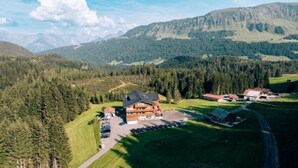 Un refugi amb un edifici gran, zona d'aparcament i paisatge forestal al voltant.