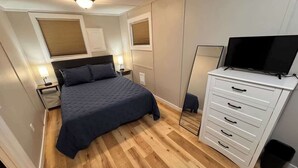 A bedroom with a bed, bedside lamps, a television, and a dresser.