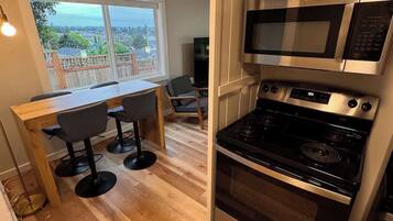 A compact kitchen with a view to the outside, a dining area with a table and chairs, and a built-in oven and microwave.
