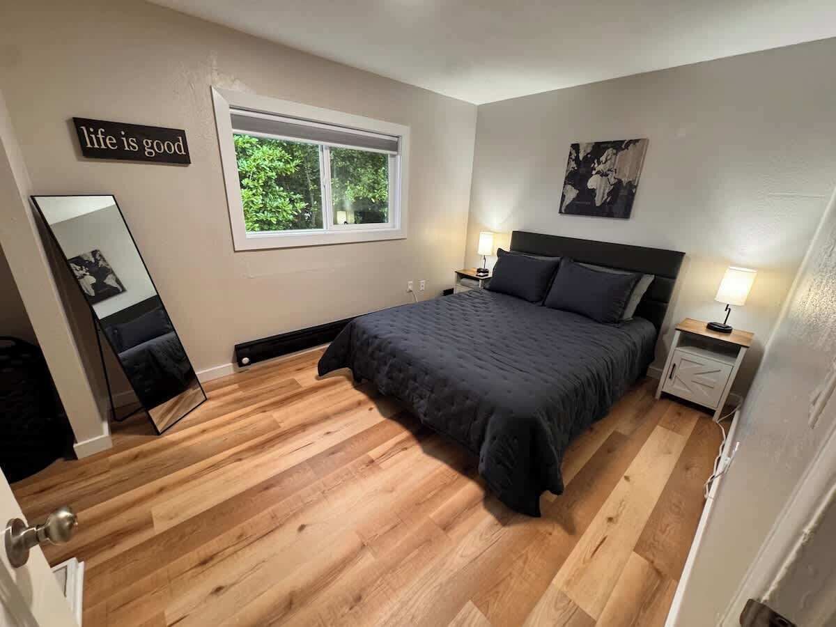 A bedroom with a bed, bedside tables, a window, and a mirror.