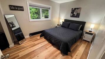 A bedroom with a bed, bedside tables, a window, and a mirror.