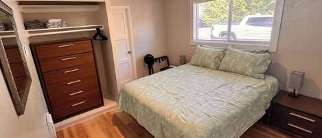 Une chambre à coucher comprenant un lit, une commode, un placard et une fenêtre donnant sur l’extérieur.
