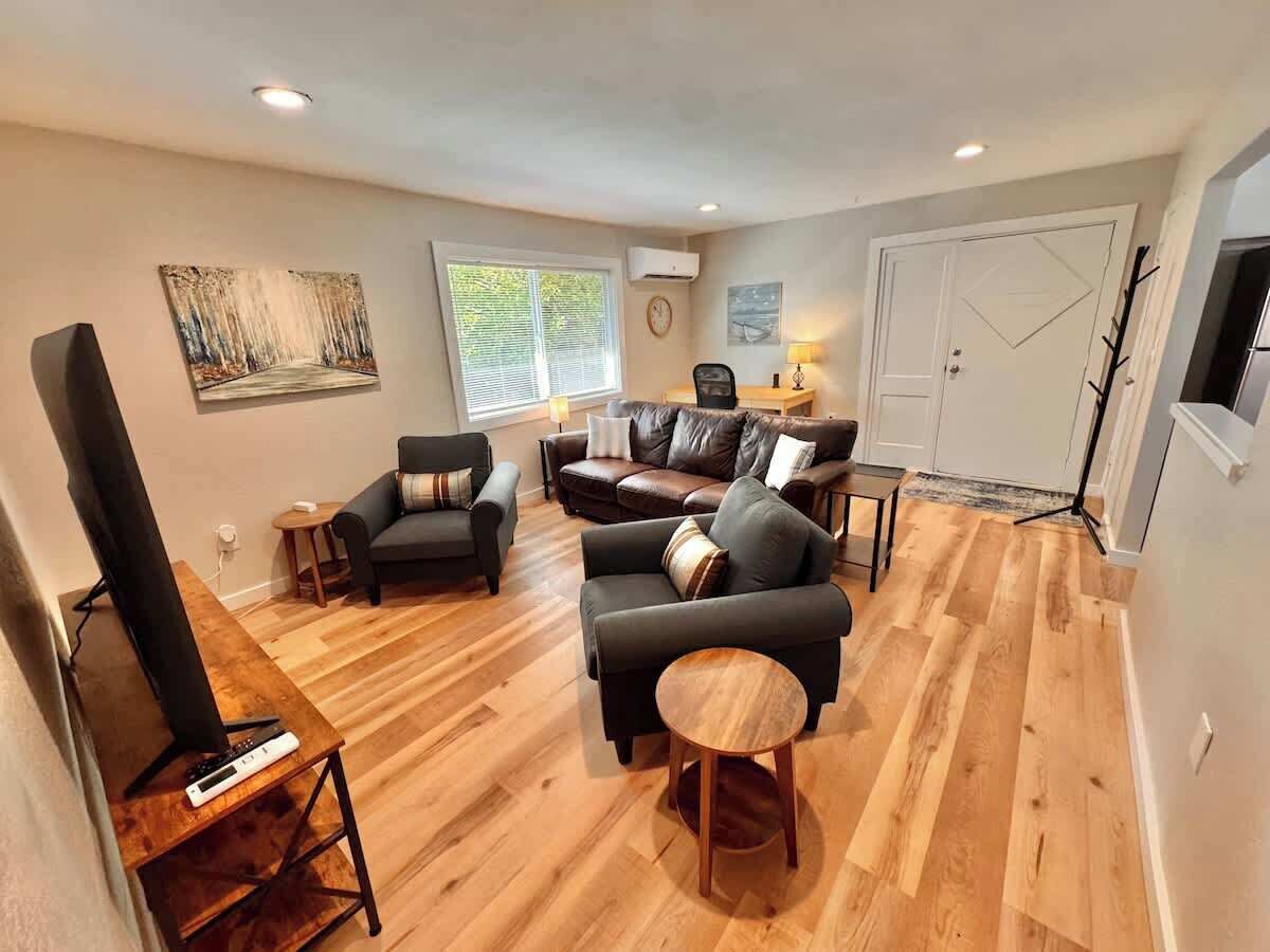 Een woonkamer met een open haard, een televisie en een eethoek met een tafel en stoelen.