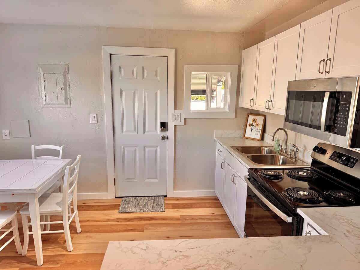 A modern kitchen with white cabinetry, a stainless steel stove, and a microwave.