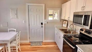 A modern kitchen with white cabinetry, a stainless steel stove, and a microwave.