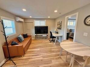 A modern living room with a sofa, TV, and dining table. - Modern Cottage near Park/Lake Access (Bremerton)