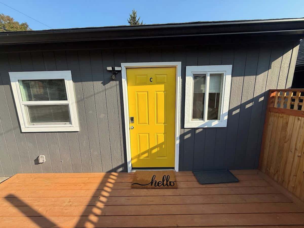 A house with a yellow door, a wooden deck, and a 'hello' mat.