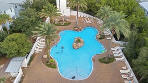 Piscina com design diferenciado, rodeada por espreguiçadeiras e palmeiras.