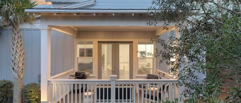 A two-story house with a covered porch and a small deck.