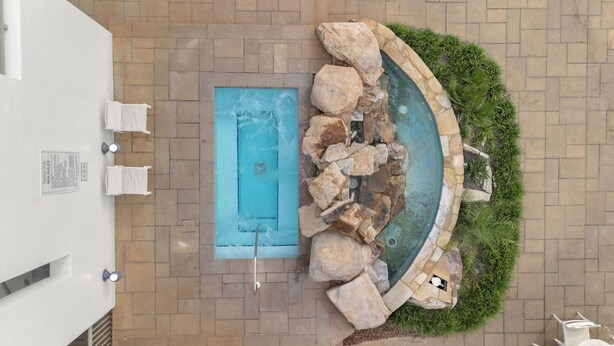 Piscina no terraço, com borda de pedra e uma pequena cascata.